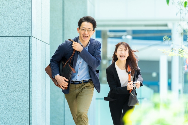 オフィス街を走る笑顔の男女ビジネスマン