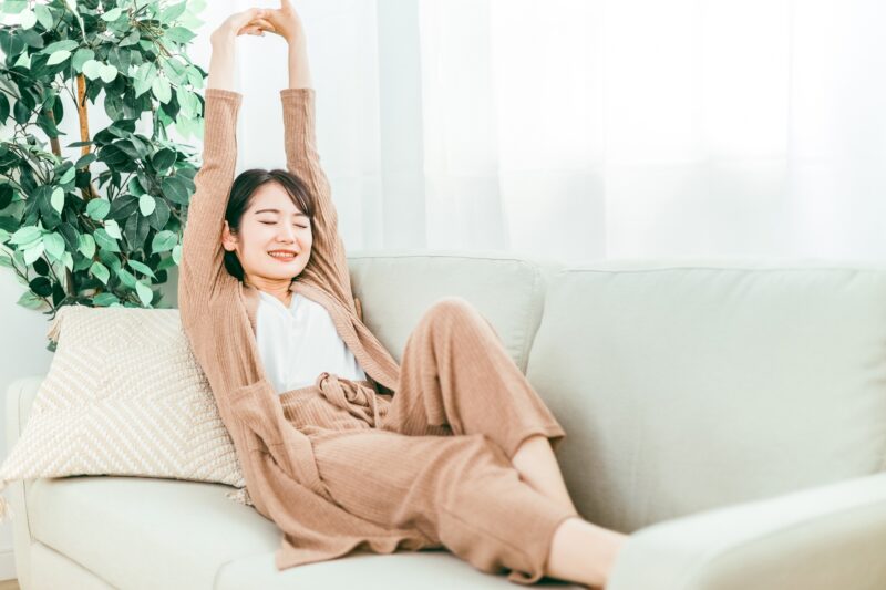 ソファでストレッチする女性(深呼吸)