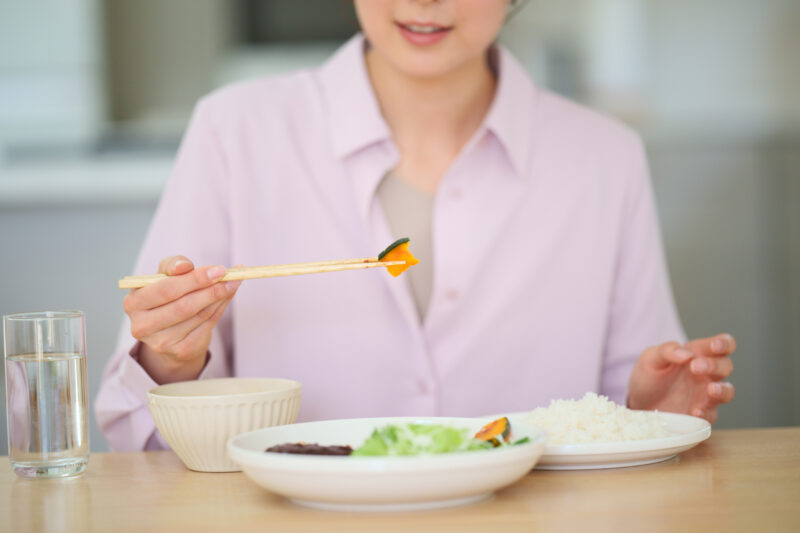ダイニングテーブルで食事をする女性