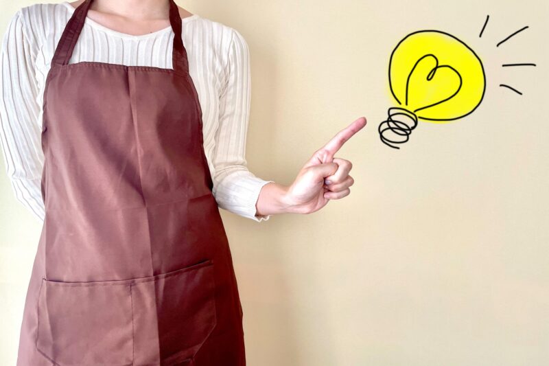 アイデアをひらめくエプロン姿の若い女性