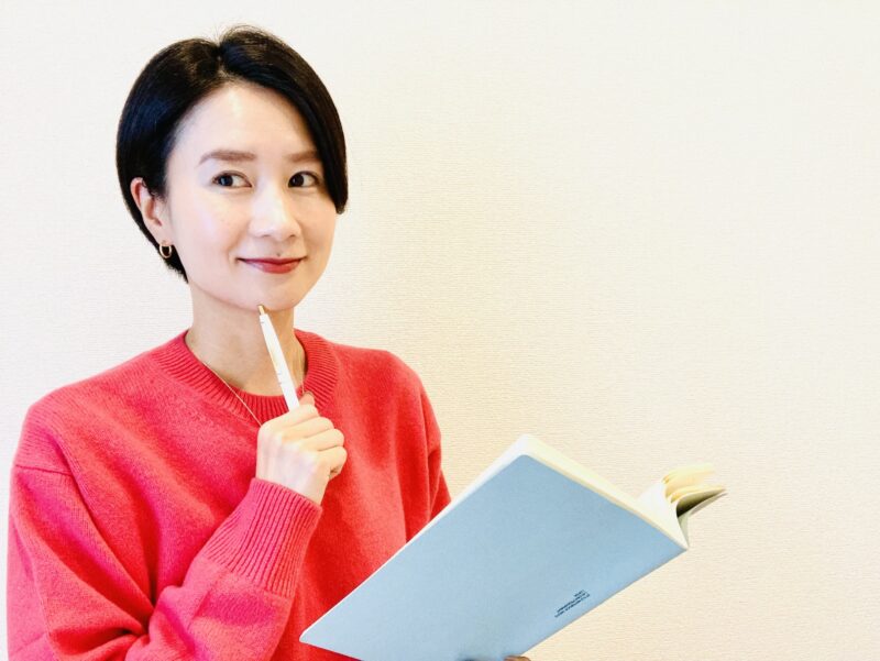 アイデアをノートに書こうとする笑顔の女性