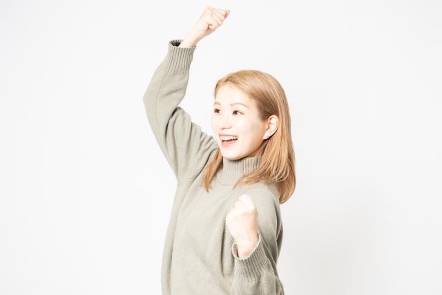 ガッツポーズをするセーターを着た若い女性