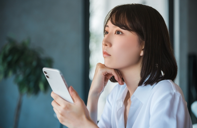 スマホを見て考える若いビジネスウーマン