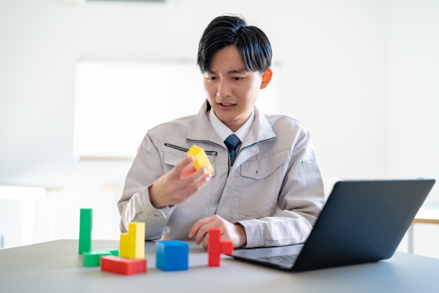 積み木を持つ作業を着た男性