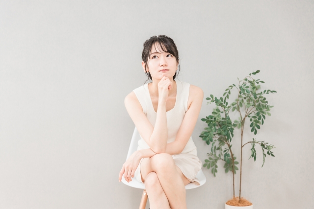 椅子に座って考える・悩むアジア人女性